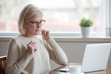 Aged woman using laptop confused seeing error message clipart