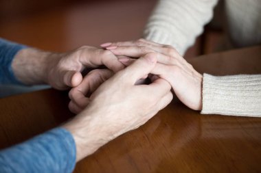 Close up of elder couple holding hands giving support clipart