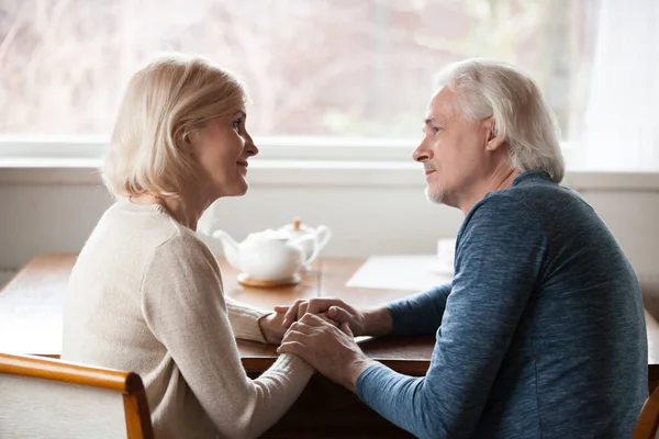 Sensual senior couple holding hands looking in the eyes