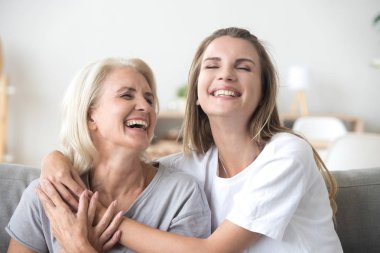 Mutlu kıdemli olgun anne kucaklayan Genç Yetişkin kadın gülüyor 