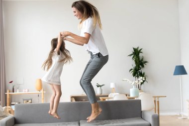 Mutlu anne ve kanepeye atlama çocuk kızı tutuşup