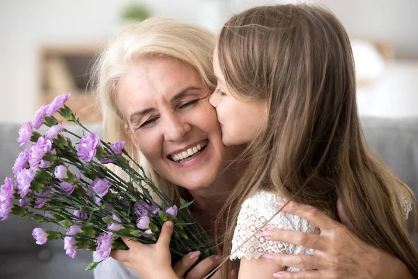 Pequeña nieta besándose dando flores ramo de felicitaciones — Foto de Stock