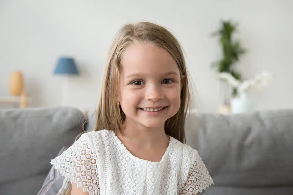 Adorable little girl looking at camera sitting on couch, portrai — Stock Photo, Image