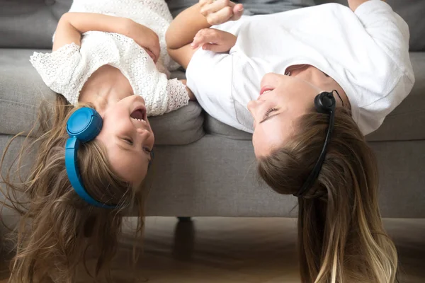 Niño y madre acostados boca abajo en los auriculares disfrutan de la música — Foto de Stock