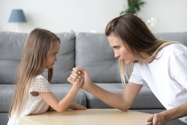 Serious mom and kid daughter arm wrestling having confrontation — Stock Photo, Image