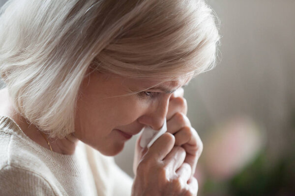 Close up of disappointed aged woman wiping tears crying 