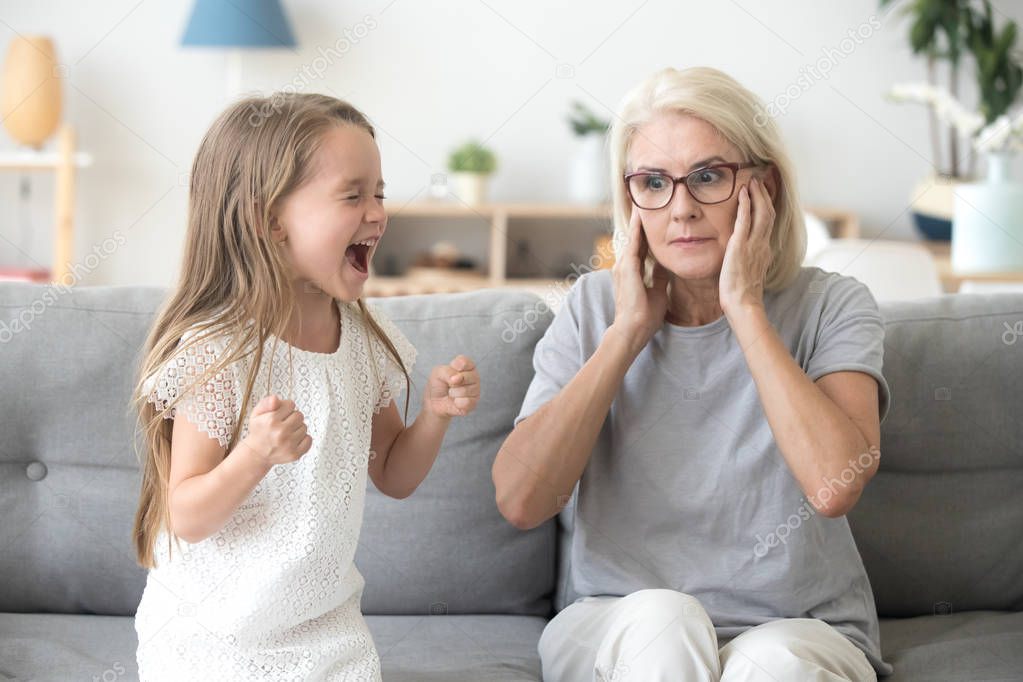 Shocked grandma closing ears not to hear stubborn granddaughter 