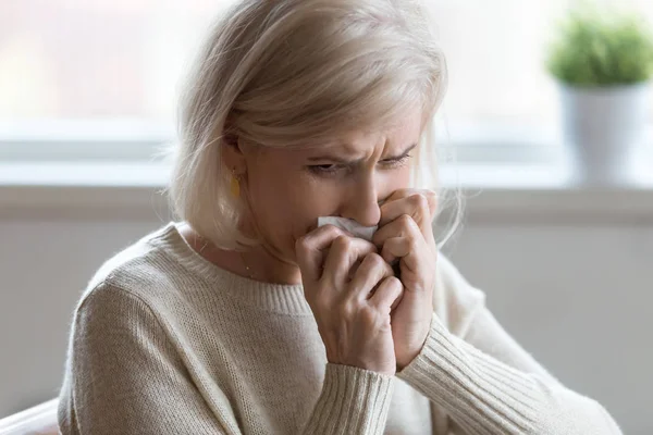 Upset aged woman crying at home feeling unwell or lonely