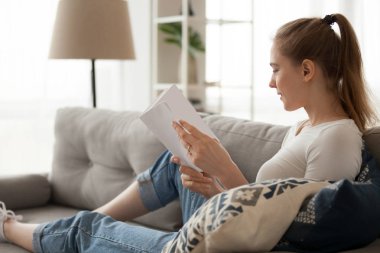 Kız evde kanepede kitap okumak rahatlatıcı