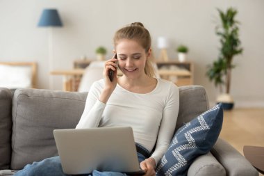 Gülümseyen kadın evden internet tarama Smartphone cep telefonu ile konuşmak