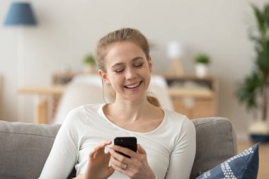 Mutlu kız smartphone kullanarak gülümseyen kanepede relax