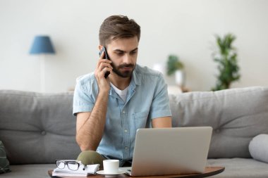 Ciddi adam konuşmak Smartphone cep telefonu ile dizüstü evde kullanma