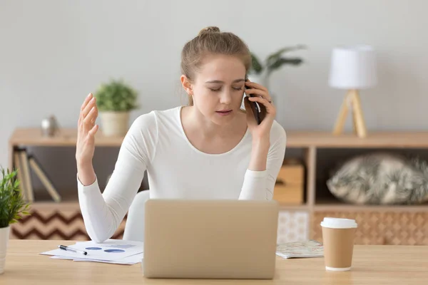 Upset female working ta laptop having unpleasant talk on phone — Stock Photo, Image