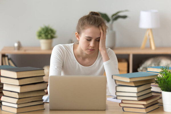 Tired girl fall asleep sitting at table with books around