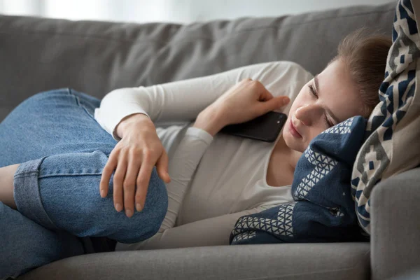 Ideges női feküdt a kanapén smartphone kezében — Stock Fotó