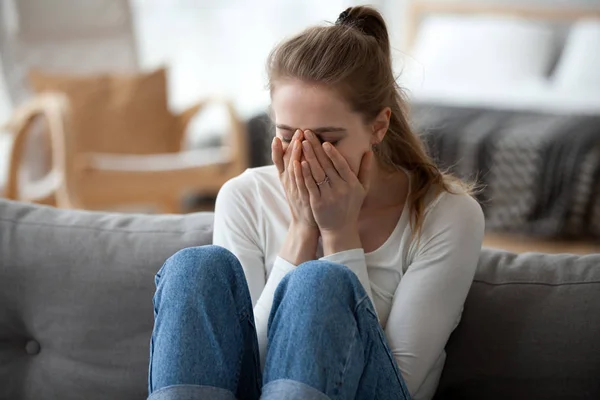 Расстроенная девушка сидит на диване и плачет после разрыва — стоковое фото
