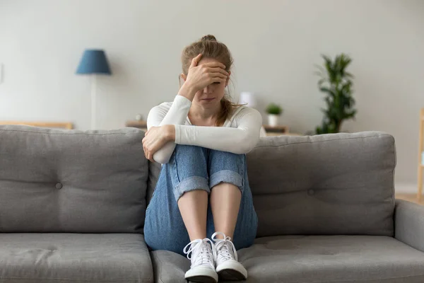 Несчастная женщина сидит на диване и грустит дома. — стоковое фото