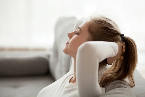 Спокойная молодая женщина отдыхает на диване дома — стоковое фото
