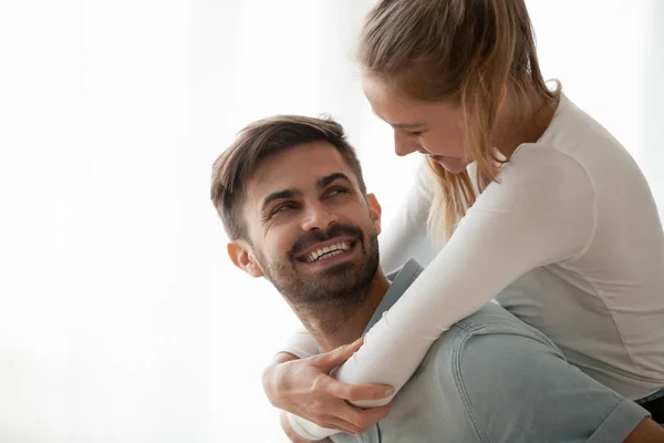 Happy millennial wife piggyback smiling husband having fun at ho — Stock Photo, Image