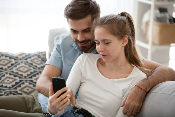 Couple millénaire se détendre sur le canapé en utilisant un smartphone — Photo