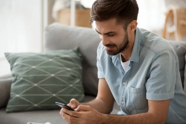 Smiling male relax at home couch using smartphone — Stock Photo, Image