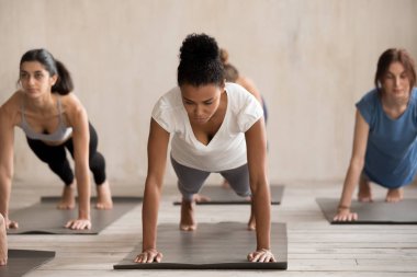 Bir grup insan pratik yoga, tahta poz yapıyor