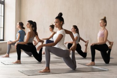 Grup Genç kadını pratik yoga, at binici egzersiz yaparak