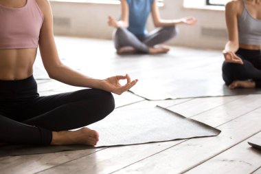 Genç bir kadın ve bir grup insan Sukhasana poz