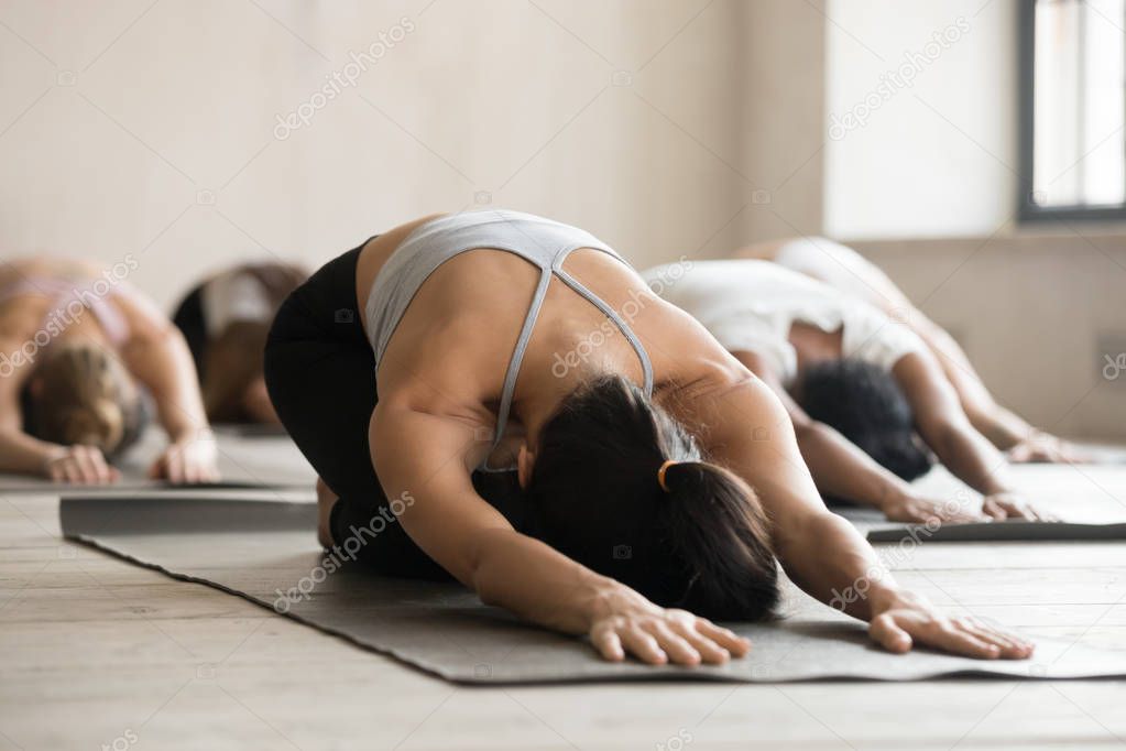 Group of sporty people practicing yoga lesson, doing Child exerc