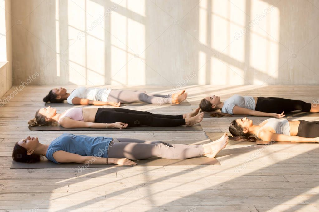 Group of young people practicing yoga lesson doing Dead Body