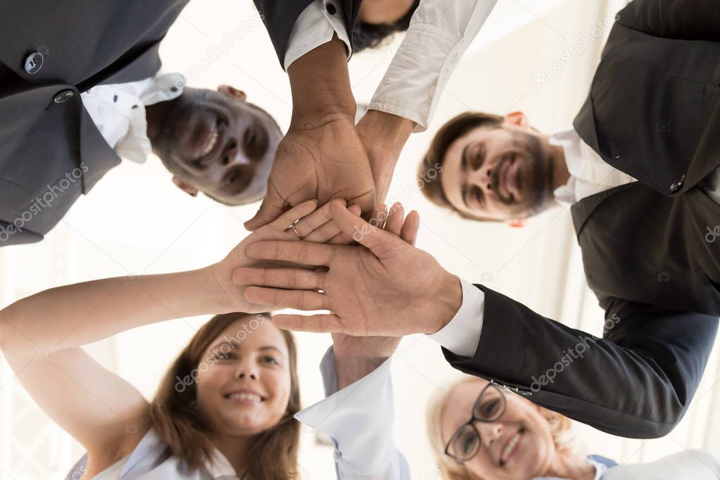 Diverse business team put hands together as concept of teambuild
