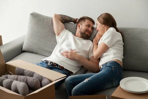 Young couple lying together at sofa, looking to each other — Stock Photo, Image