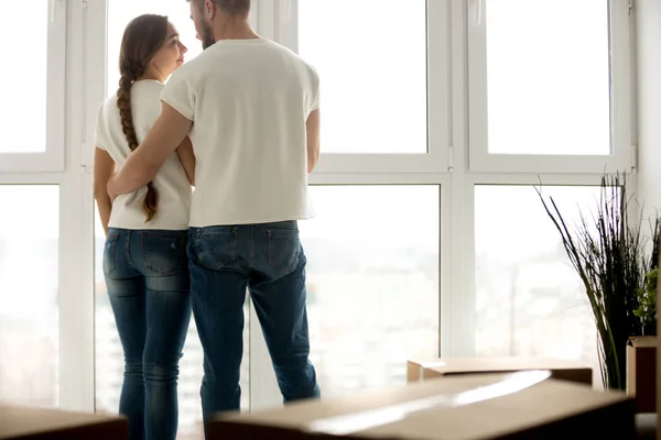 Молодая пара обнимается в новой квартире с упакованными вещами — стоковое фото