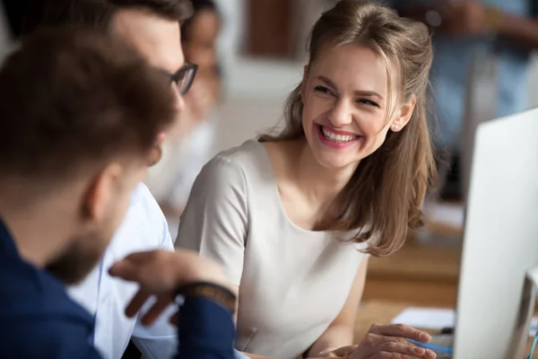 Sorridente giovane donna che parla con i colleghi sul posto di lavoro condiviso — Foto Stock