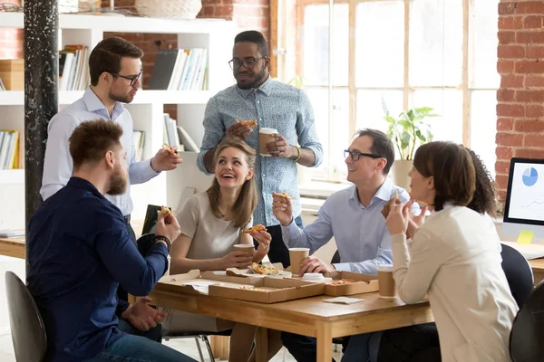 Multiracial work team eating pizza together on break