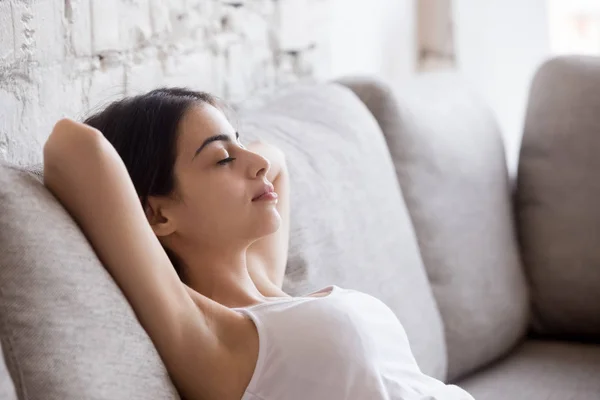 Молодая женщина расслабляется, опираясь на удобный диван — стоковое фото