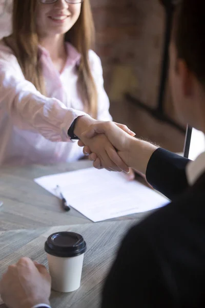 Vriendelijke aantrekkelijke jonge vrouw handshaking man bij vergadering. — Stockfoto