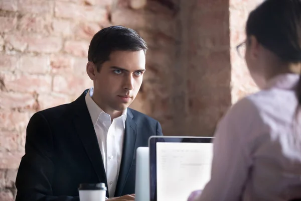 Hombre de negocios mirando a la joven mujer detrás de la computadora portátil . — Foto de Stock