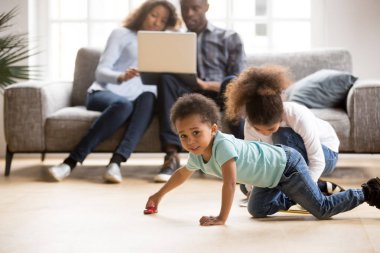 African American married couple using laptop while children play clipart
