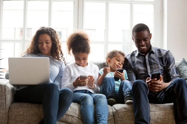 Grande famiglia afroamericana utilizzando dispositivi, seduti insieme — Foto Stock