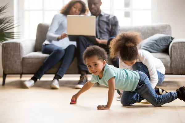 African American married couple using laptop while children play — Stock Photo, Image