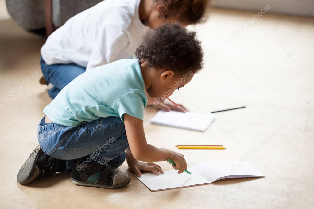 Little African American children drawing with colorful pencils