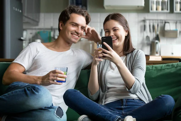 Jóvenes pareja juntos se divierten con los teléfonos inteligentes en casa — Foto de Stock