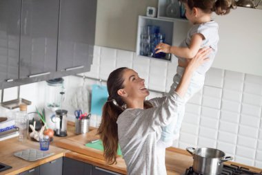 Mutlu gülümseyen anne holding kızı mutfakta