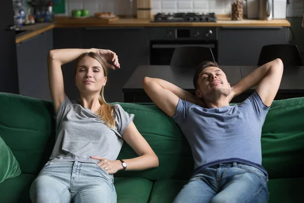 Молодий чоловік і жінка сидять разом на дивані, розслабляючись — стокове фото