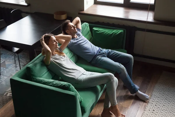 Joven hombre y mujer sentados juntos en el sofá, relajante — Foto de Stock