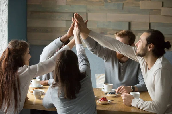 Happy friends meeting in cafe giving high five for friendship