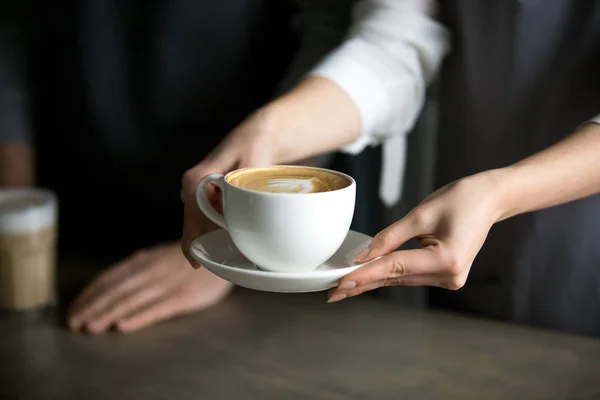 Close up of barista serving aromatic cappuccino to visitor — Stock Photo, Image