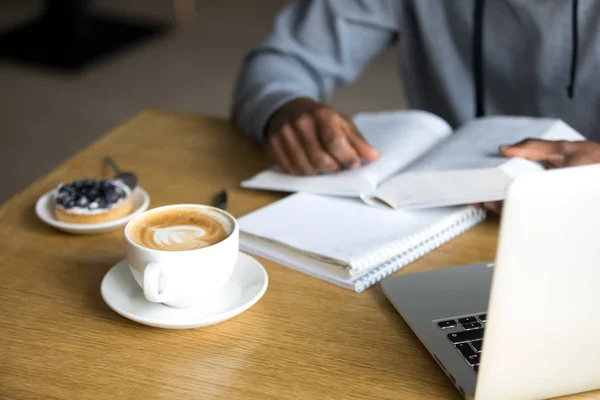 Close up of cappuccino cup served to black cafe visitor — Stock Photo, Image