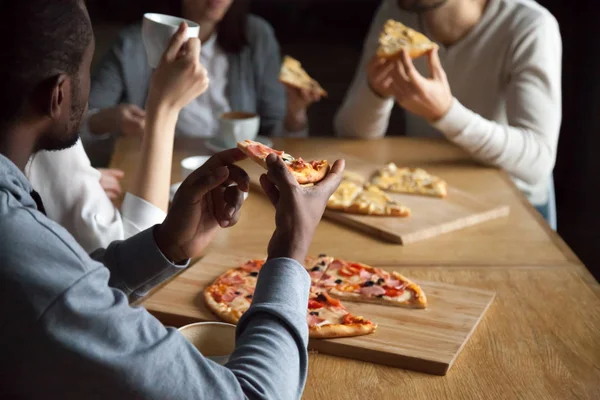 Close up of diverse friends eating pizza out